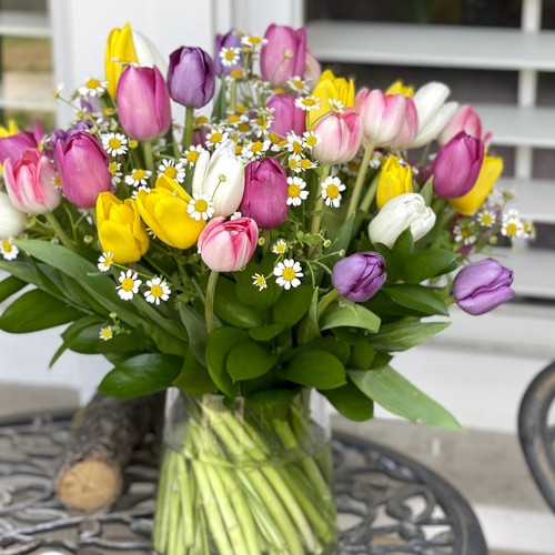 Colorful tulips in yellow pink and purple with chamomile daisies in a glass vase from flower studio Durham