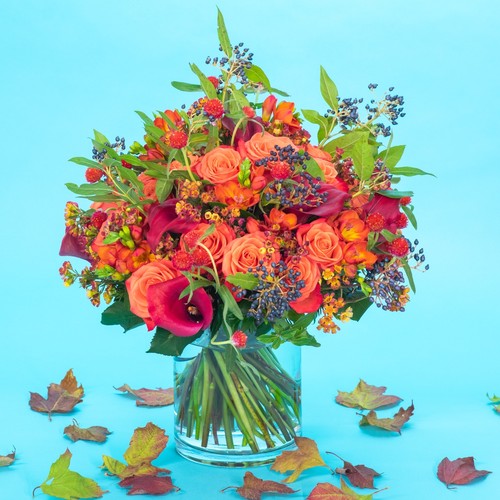Autumn bouquet of orange roses calla lilies and berries with fallen leaves from Durham flower delivery