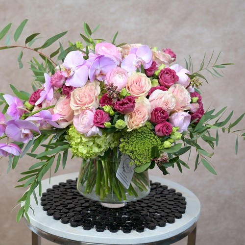 Lavender orchids blush roses and green hydrangea in a glass vase on a modern table by Durham flower studio