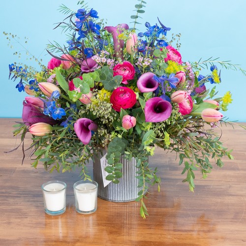 Vibrant ranunculus calla lilies and blue delphinium in a galvanized tin vase from flower studio Durham NC