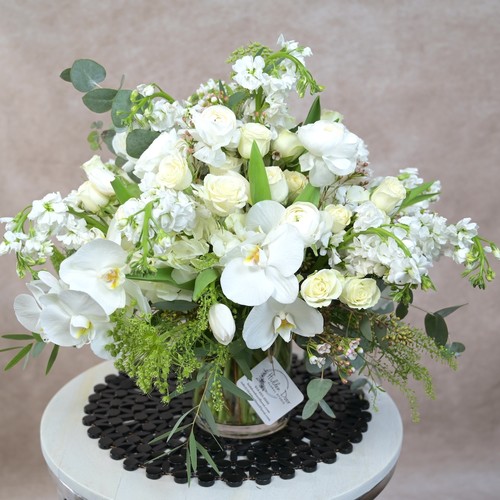 All white orchids roses stock and tulips with eucalyptus in a glass vase by Durham floral studio