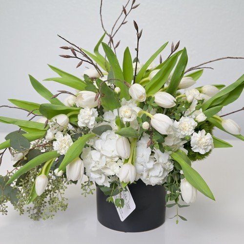 White tulips hydrangea and carnations with willow branches in a black vessel from flower studio Durham NC